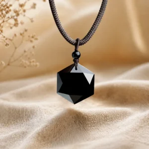 Obsidian pendant on dark gray velvet surface, root chakra protection crystal jewelry