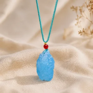 Aquamarine pendant hanging on chain above dark gray suede fabric for elegant jewelry display